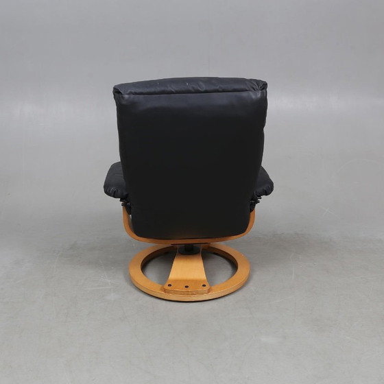 Image 1 of Sweden-origin Scandinavian lounge armchair with a matching ottoman, featuring a black leather and wood frame, in good condition 
