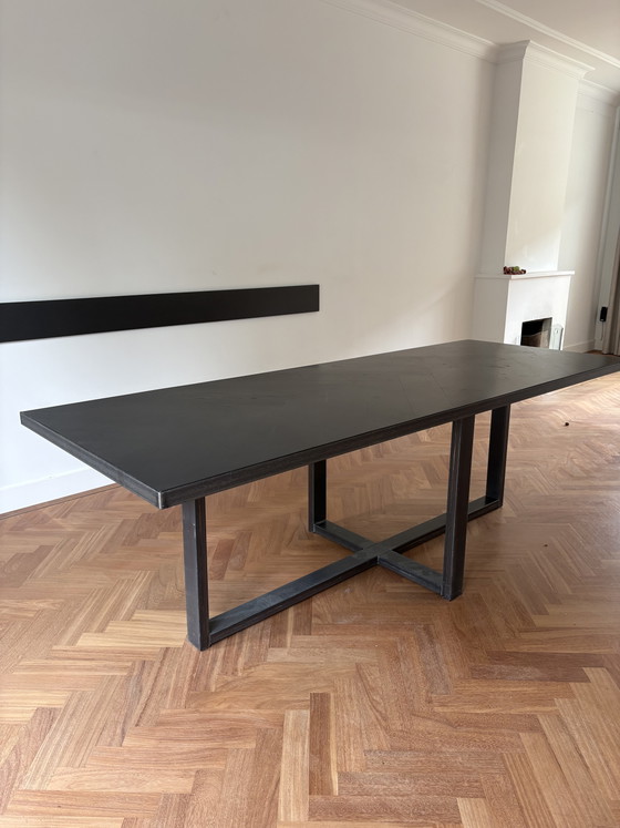 Image 1 of Mesa elegante y delgada de madera negra con estructura de acero.
