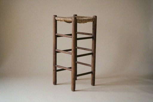 Taburete alto de madera con asiento de junco.