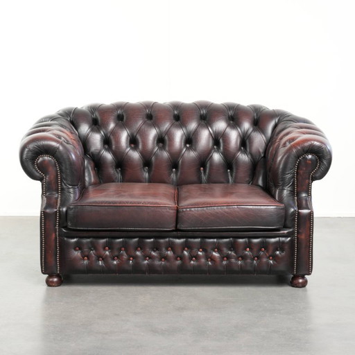 Canapé Chesterfield 2 places en cuir de vachette anglais ancien rouge/marron, au style magnifique et au charme intemporel.
