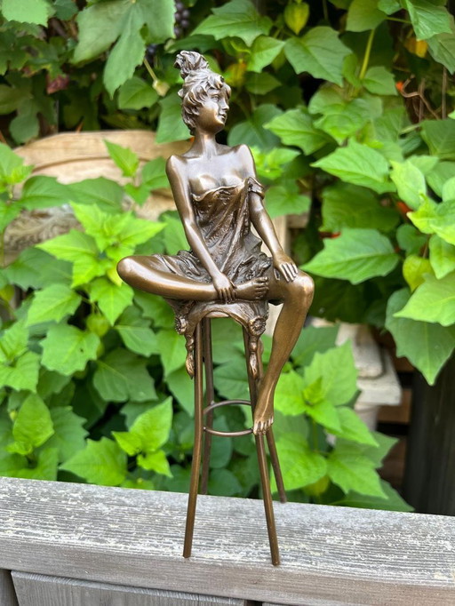 Bronzeskulptur einer auf einem Hocker sitzenden Dame