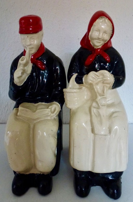 Een stel decoratieve boekensteunen van een ouder echtpaar, zittend op stoelen.