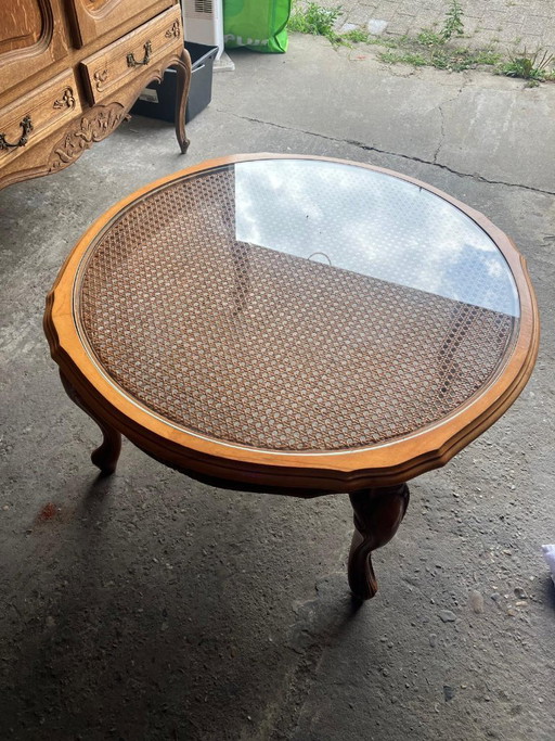 Vintage oval coffee table in French Louis XV style is made of cherry wood and features a glass top over wicker weaving.