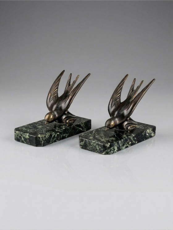 Image 1 of Een paar art-deco boekensteunen – zwaluwen van gepatineerd zink op groene marmeren voetstukken.