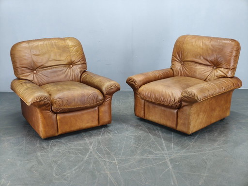 Een paar Arcon Italia loungefauteuils van cognacbruin buffelleer.