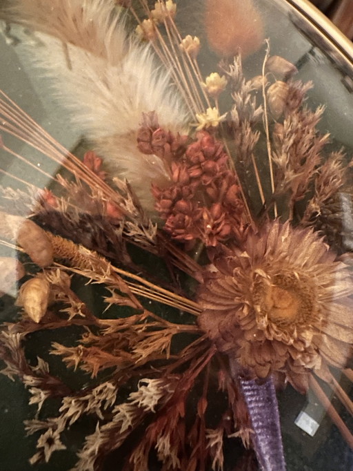 Wall decoration of dried flowers behind curved glass
