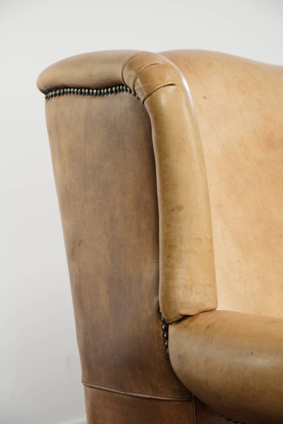 Image 1 of Dos hermosos sillones orejeros de piel de vaca clara con un estilo inglés atemporal y gran comodidad.