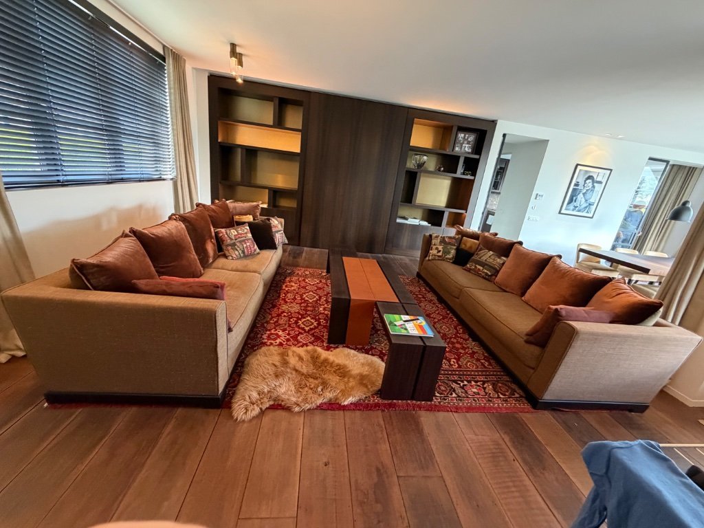 Deux fauteuils Promemoria Wanda en tissu cappuccino avec 8 coussins Promemoria et un tapis iranien assorti.