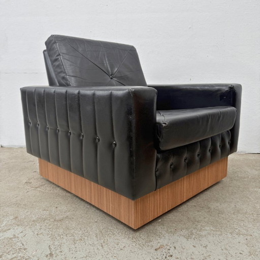 Sillón de diseño moderno de mediados de siglo en cuero negro con pedestal de madera.