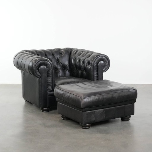 Set of a black cowhide Chesterfield armchair and footstool