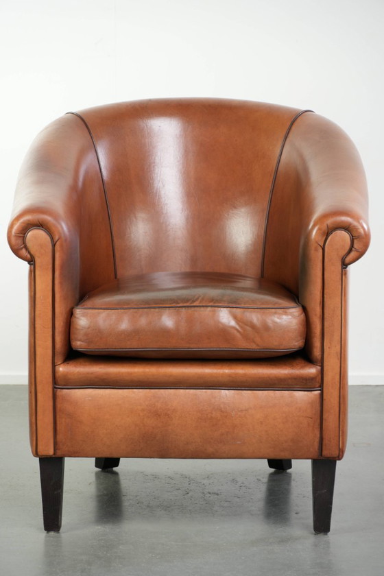 Image 1 of Vintage schapenleren clubfauteuil met een warme kleurstelling en afgewerkt met zwarte biezen