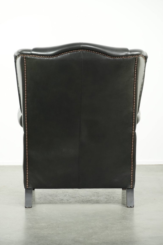 Image 1 of Zwarte rundleren oorfauteuil in een klassiek Engelse stijl