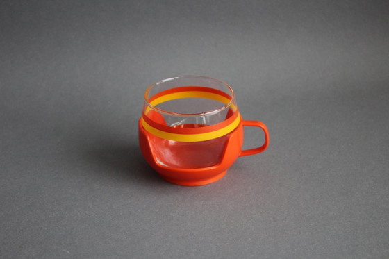 Image 1 of 12 vintage glazen theekopjes met geel-oranje strepen en oranje plastic houders.