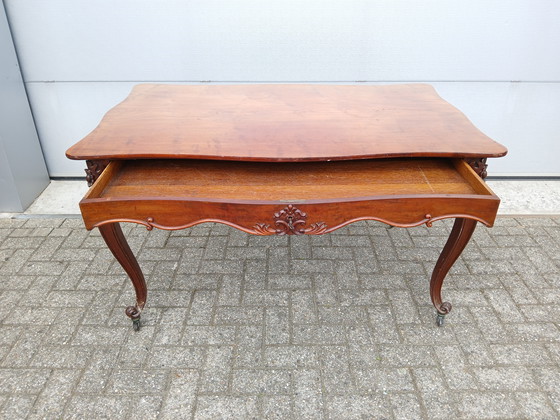 Image 1 of The antique dining table is made of mahogany and has a Louis XV style.