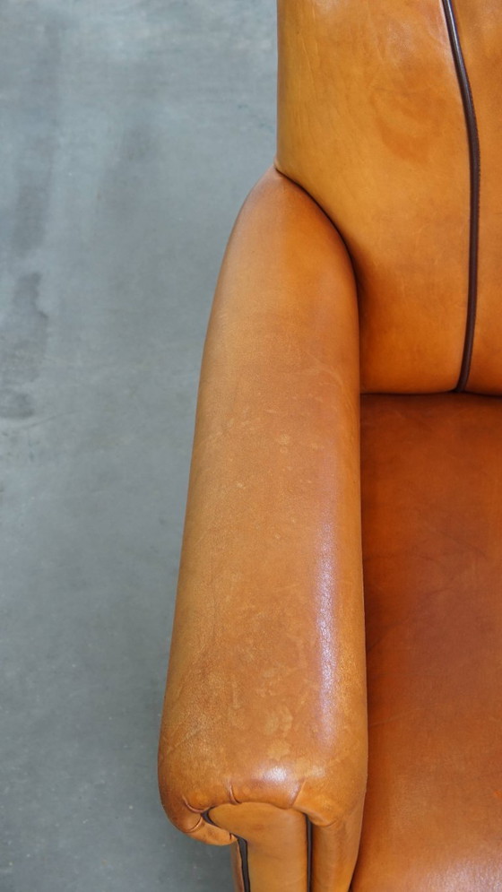 Image 1 of Schapenleren armchair met een afwerking met donkerbruine biezen