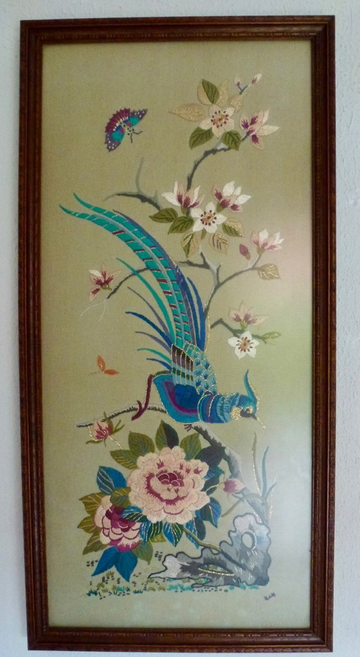 Vintage hand-embroidered wall tapestry, behind glass, with a crane, butterflies and flowers.
