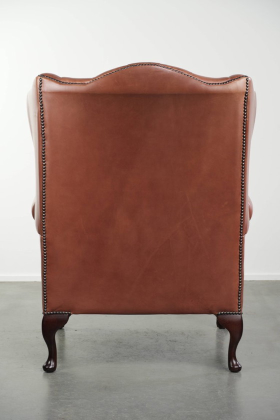 Image 1 of Fauteuil Chesterfield à oreilles en cuir de vachette anglais, assise capitonnée, avec une belle patine et de jolies couleurs.
