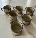 Vintage enameled stoneware cups and milk jug with floral pattern