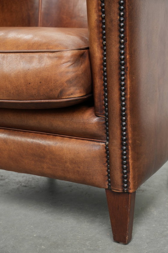 Image 1 of Poltrona club in montone color cognac caldo, rifinita con borchie decorative.
