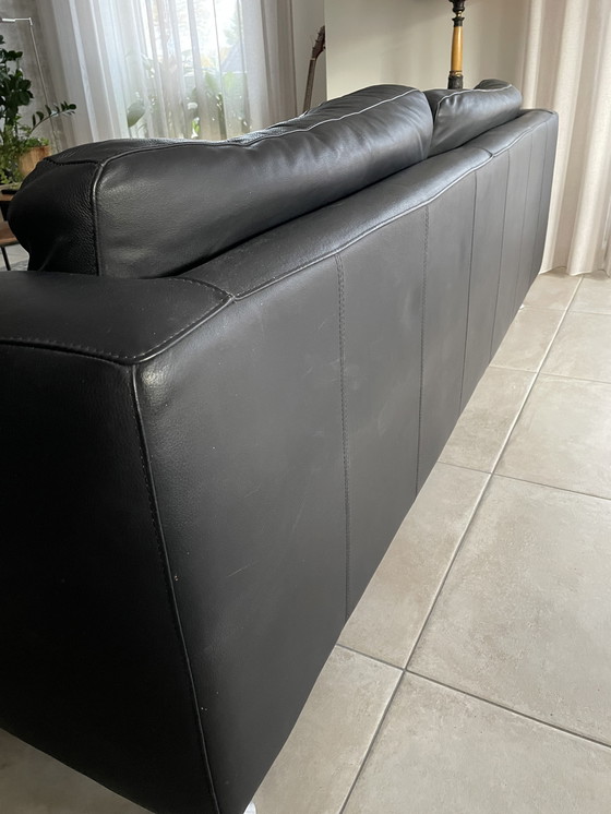 Image 1 of Black leather three-seater sofa.
