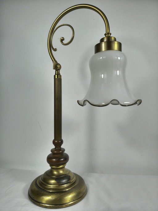 Lámpara de mesa vintage de latón con pantalla de cristal opalino y brazo decorativo clásico.