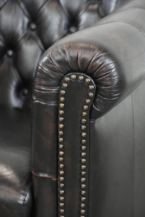 Image 1 of Donkere luxe rundleren Chesterfield clubfauteuil in Engelse stijl, afgewerkt met siernagels