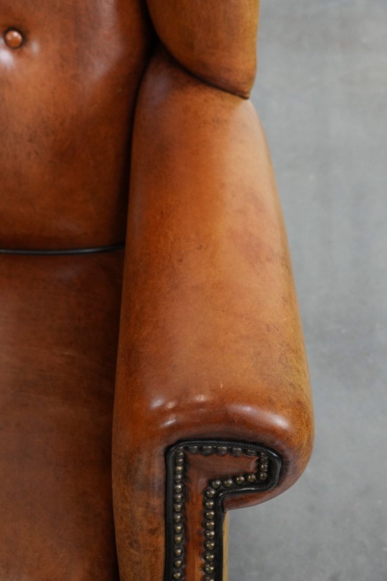 Image 1 of Grote schapenleren oorfauteuil met zwarte biezen en siernagels