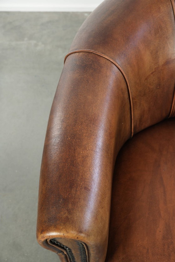 Sturdy and characterful sheepskin club armchair with a beautiful patina, finished with decorative nails. (photo 7 of 12)