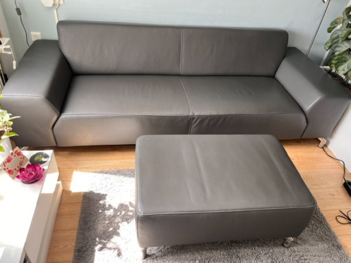 Bellissimo divano di design a 3 posti in pelle grigio/antracite + pouf abbinato.