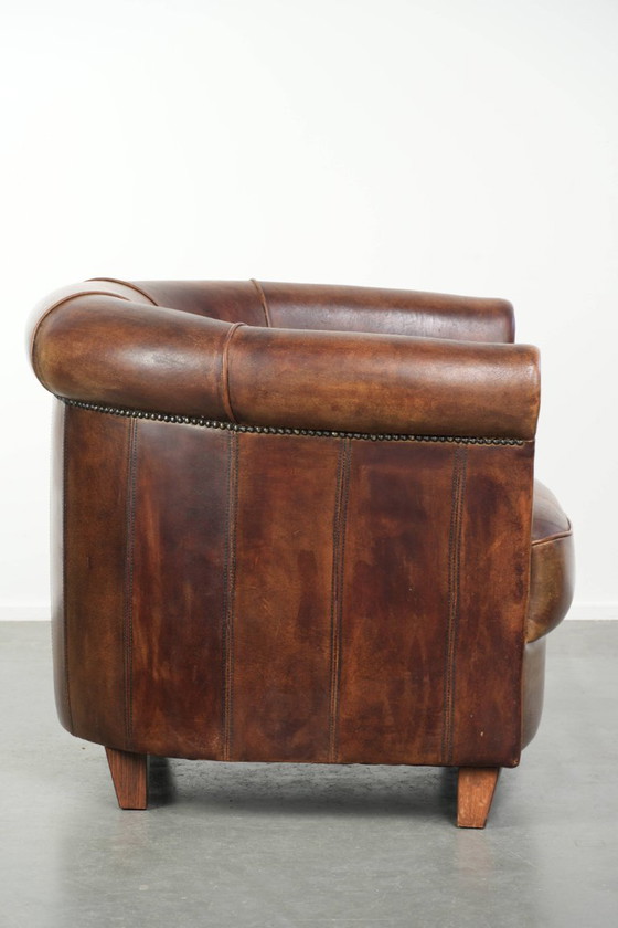 Sturdy and characterful sheepskin club armchair with a beautiful patina, finished with decorative nails. (photo 3 of 12)