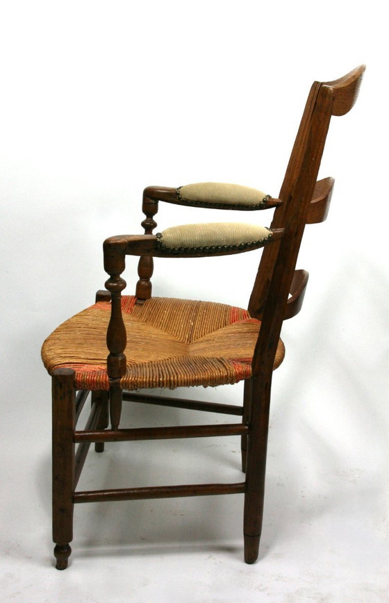 Image 1 of Antieke Frans-Provençaalse armstoel met biezenmat zitting — notenhout, gedraaide accenten, circa late 19e/vroeg 20e eeuw