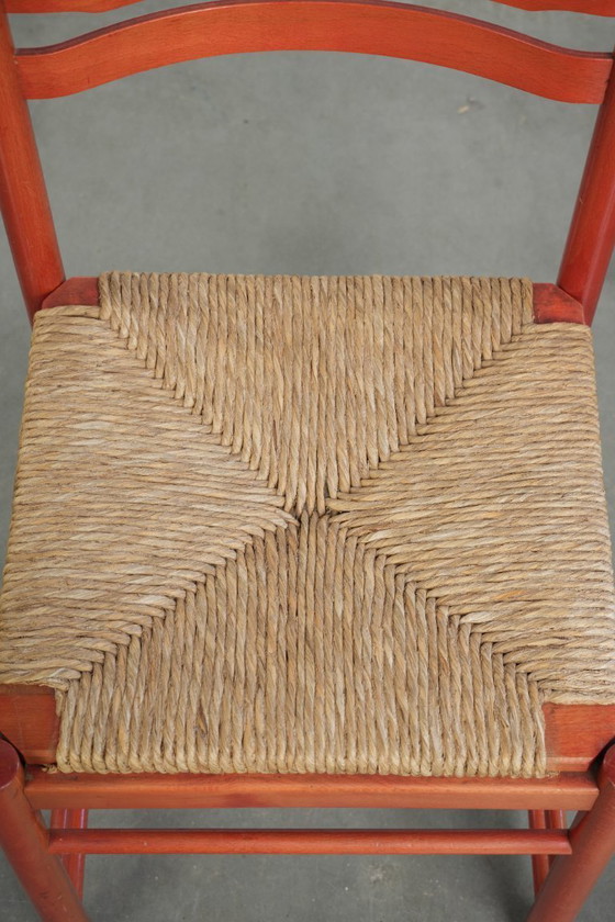 Image 1 of Schöner roter Vintage-Holzstuhl aus den 70er Jahren mit einer Sitzfläche aus geflochtenem Rohrgeflecht.