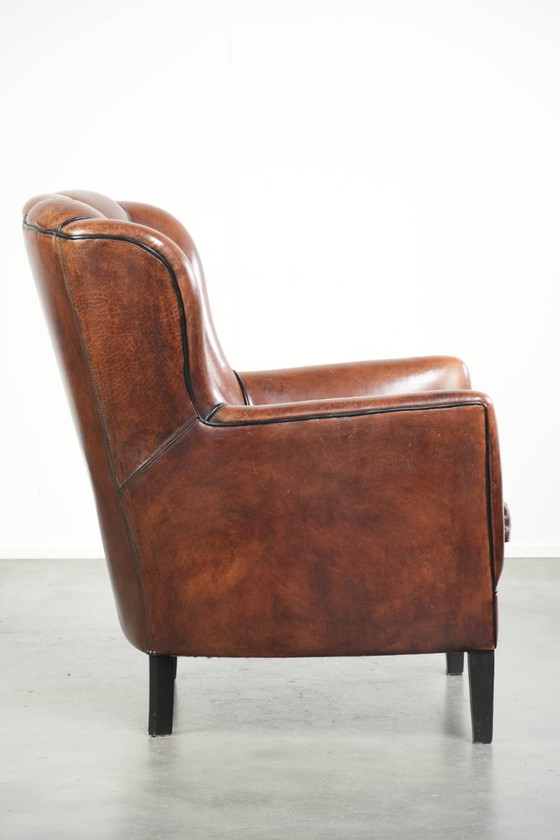 Fauteuil unique en peau de mouton aux couleurs chaudes et profondes, orné d'un passepoil noir. – Leather (photo 3 of 14)