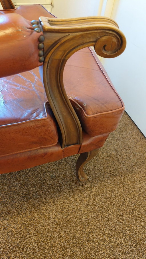ElVintage ear armchair executed in cognac sheep leather with elegant wood tooled armrest and legs
