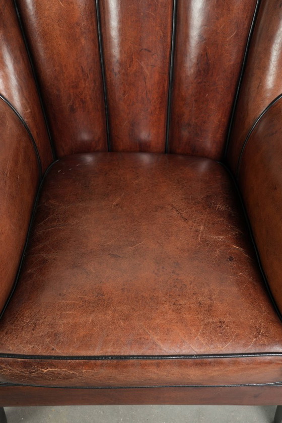 Fauteuil unique en peau de mouton aux couleurs chaudes et profondes, orné d'un passepoil noir. – Leather (photo 6 of 14)