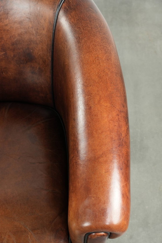 Image 1 of Mooie en karaktervolle schapenleren clubfauteuil met mooie diepe warme kleuren, zwarte biezen en een comfortabele zit