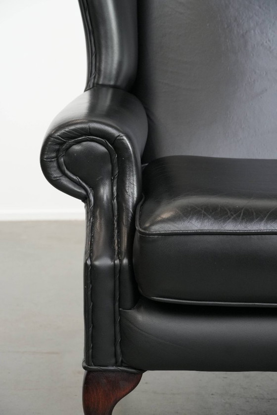 Image 1 of Smooth black cowhide Chesterfield wingback armchair in English style with color-matched piping