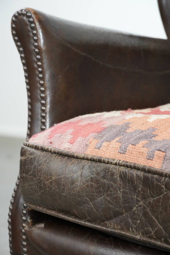 Image 1 of Subtiele donkerbruine fauteuil gemaakt van rundleer met een omkeerbaar Kelim zitkussen