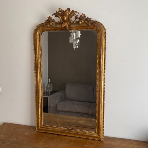 Vergulde spiegel uit de late 19e eeuw met gedecoreerd fronton. 130x74 cm.