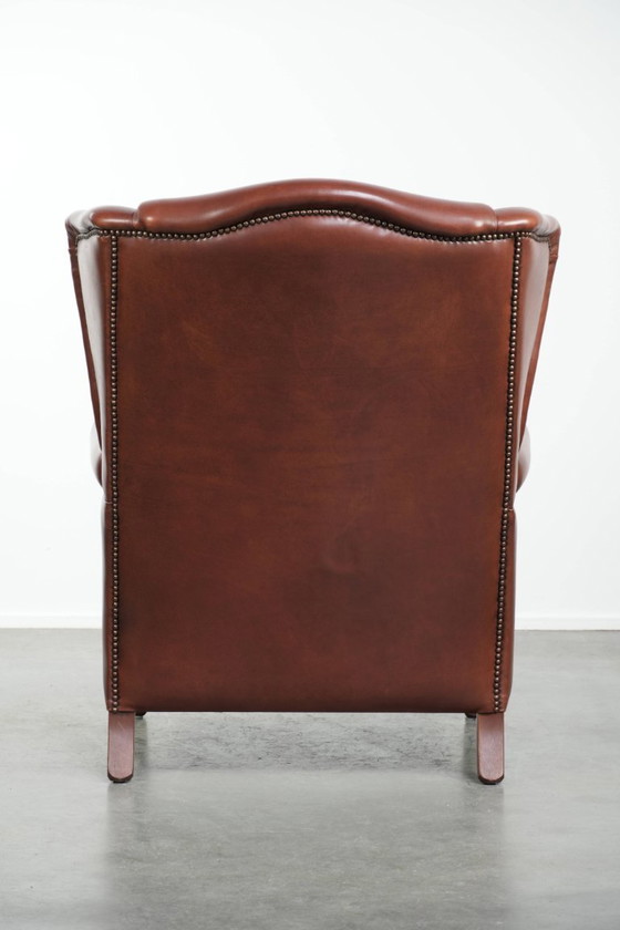 Image 1 of Comoda poltrona a orecchioni in pelle bovina color cognac in stile inglese.