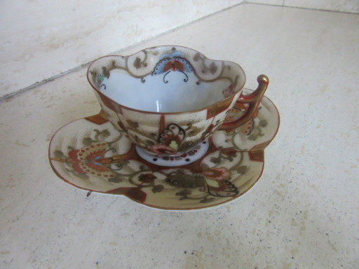 Tazza da tè e piattino orientali antichi, rossi e dorati, contrassegnati sul fondo.
