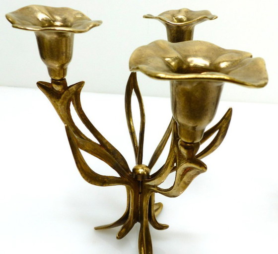 Image 1 of Een paar messing kandelaars met drie lichtpunten op een statief, versierd met organische bloemmotieven, circa 1960-1970.