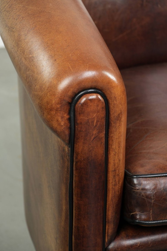 Image 1 of Mooie en karaktervolle schapenleren clubfauteuil met mooie diepe warme kleuren, zwarte biezen en een comfortabele zit