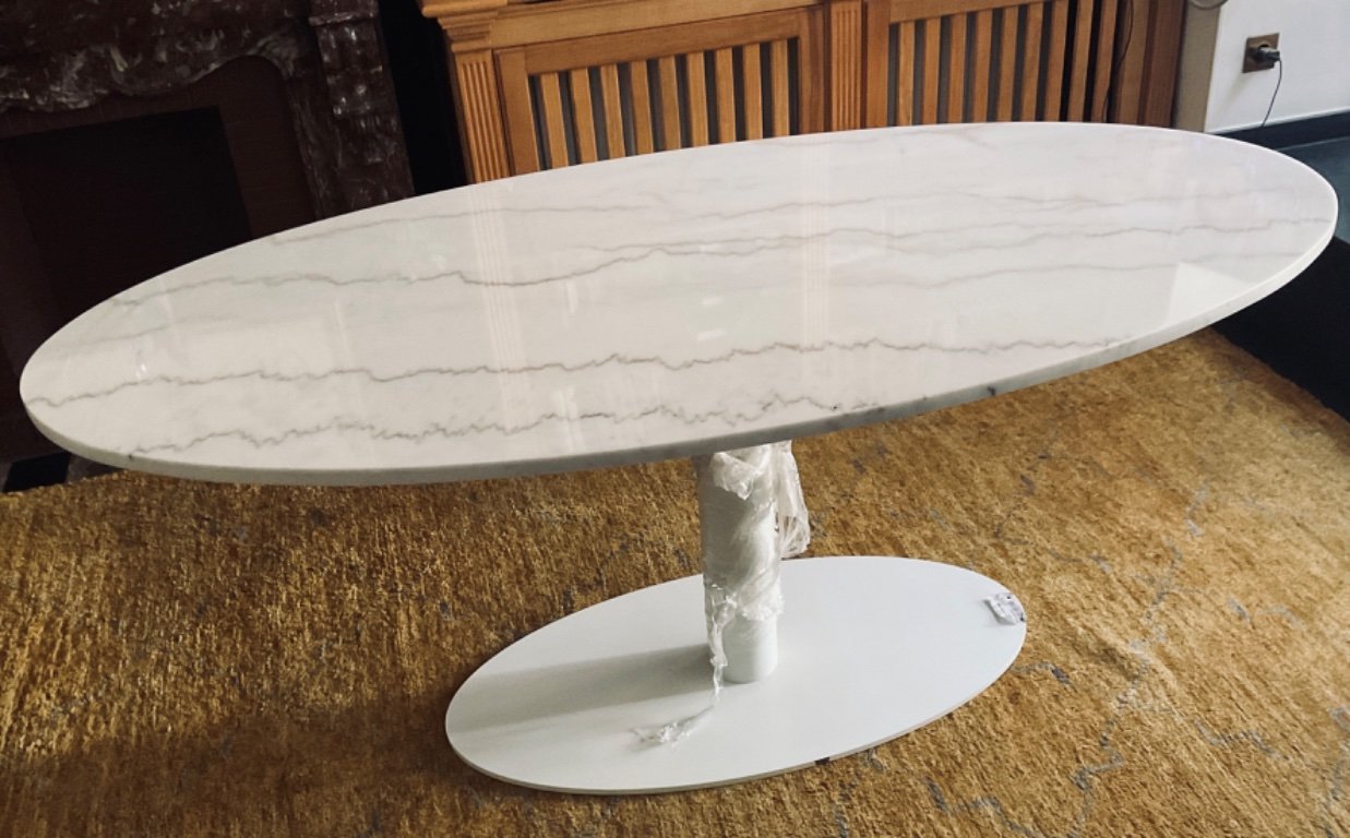 Mesa ovalada de mármol blanco.