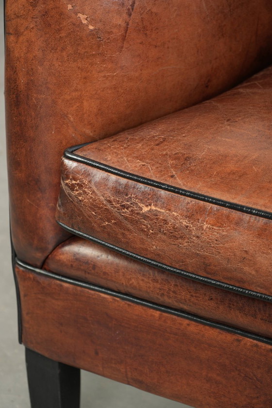 Fauteuil unique en peau de mouton aux couleurs chaudes et profondes, orné d'un passepoil noir. – Leather (photo 11 of 14)