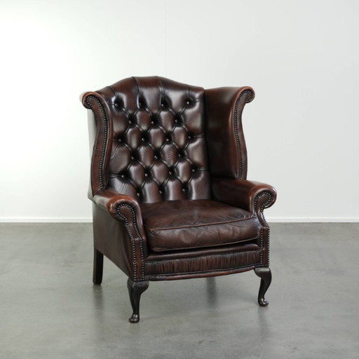 Elegante rundleren chesterfield oorfauteuil met een prachtig patina en comfortabele zit