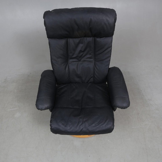 Image 1 of Sweden-origin Scandinavian lounge armchair with a matching ottoman, featuring a black leather and wood frame, in good condition 
