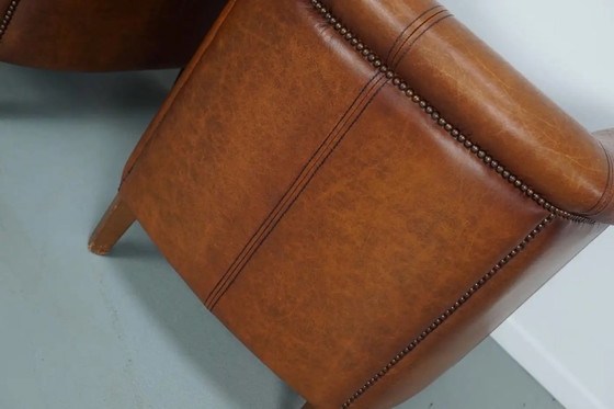 Image 1 of Dit paar cognackleurige leren clubfauteuils komt uit Nederland. Ze zijn bekleed met cognackleurig leer en zijn voorzien van meta