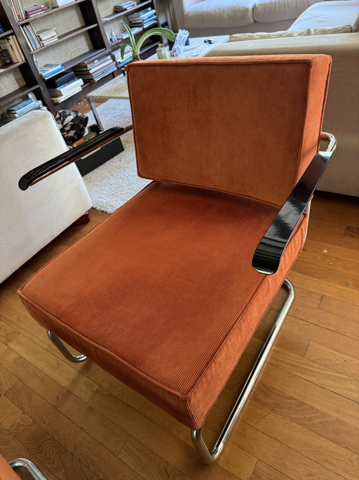 Preciosa silla con otomana de Zuiver en pana naranja y estructura tubular cromada.