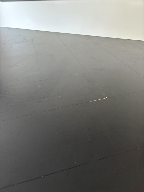 Image 1 of Mesa elegante y delgada de madera negra con estructura de acero.